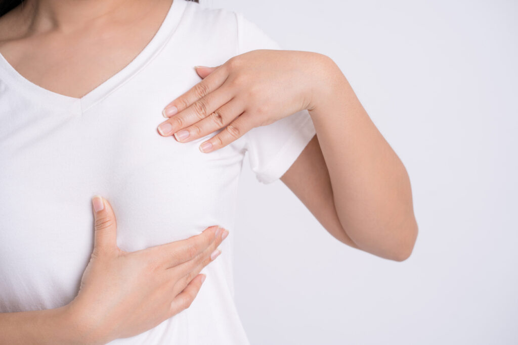 Close up of a woman cupping her breast, potentially in discomfort from breast implant illness. Close up of a woman cupping her breast, potentially in discomfort from breast implant illness.