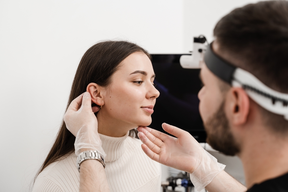 Woman having her ears examined by a cosmetic surgeon in preparation for a subtle otoplasty.