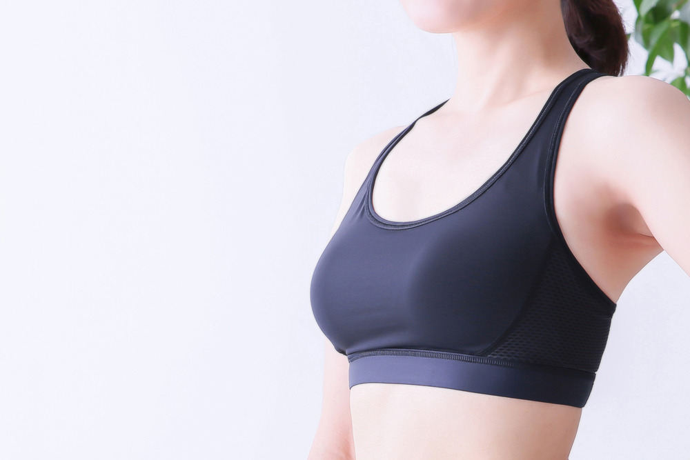 Close up of a woman in a sports bra, looking comfortable and secure after healing from a breast reduction.