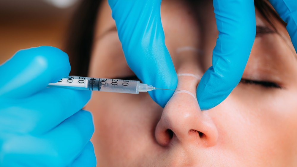 Woman receiving injections into nose for nonsurgical rhinoplasty